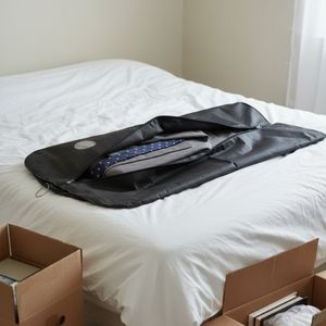 Wäschesack mit Kleidung darin auf Bett